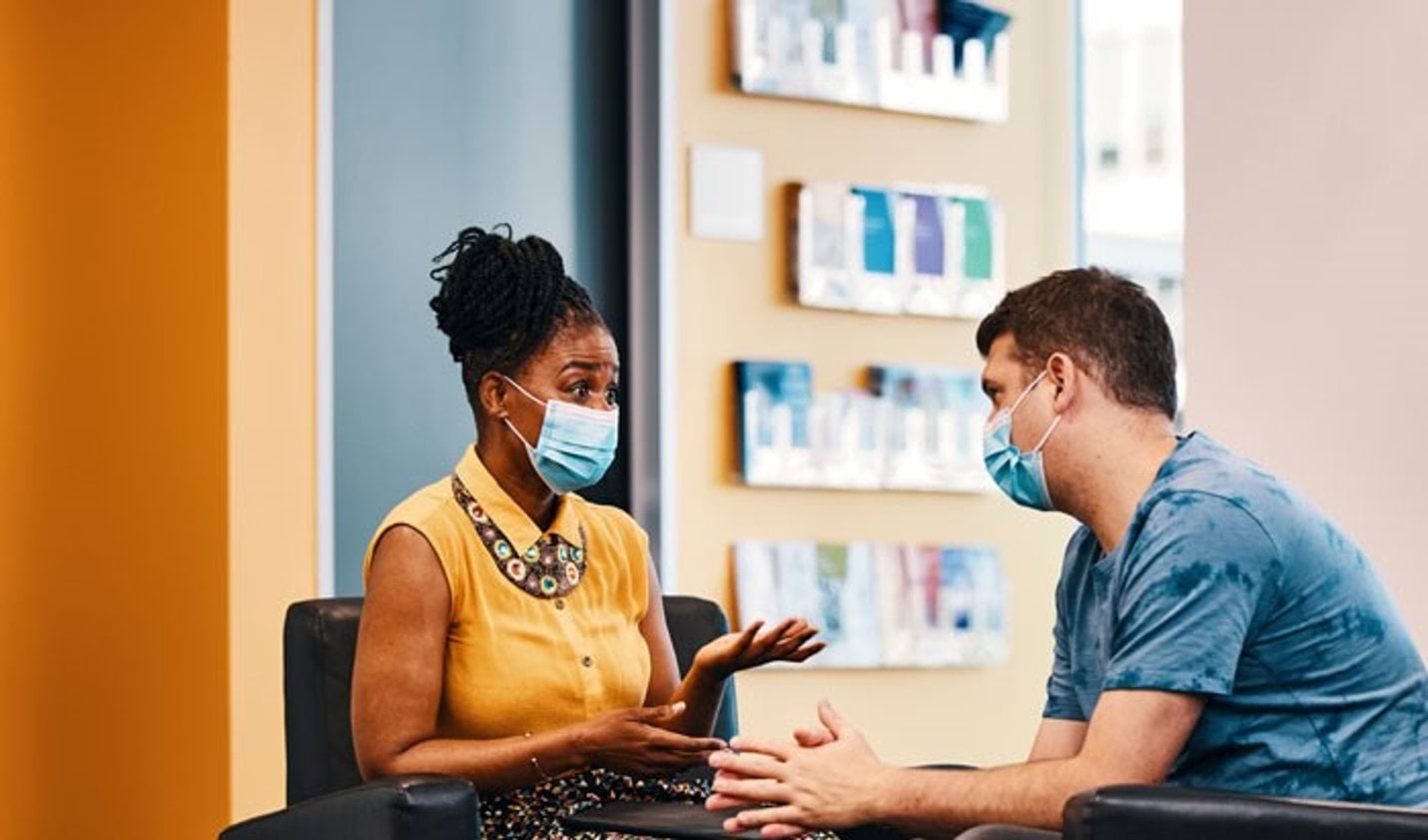 Woman and man in surgical masks having an animated conversation in a medical setting