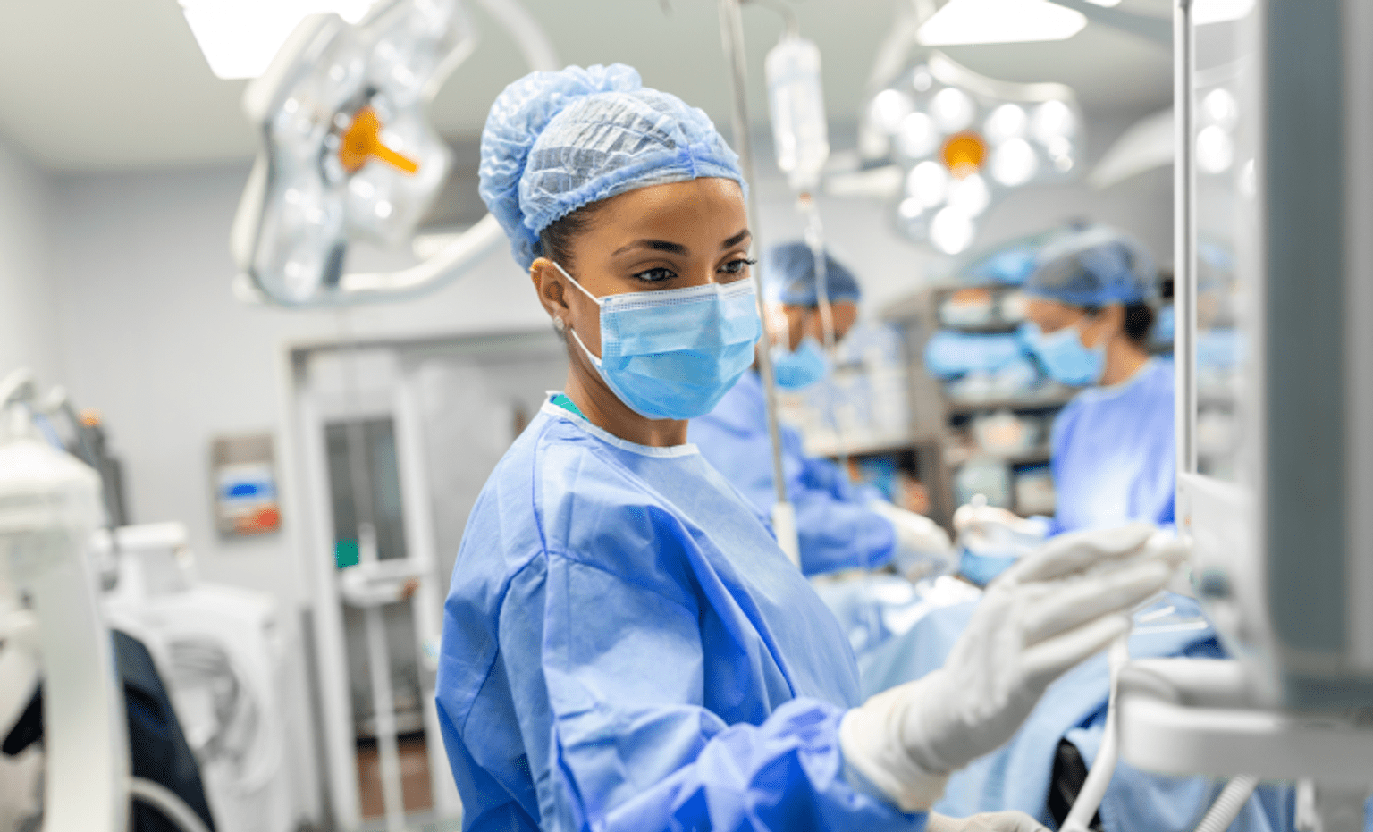 A woman operating a machine in an operating theatre in PPE