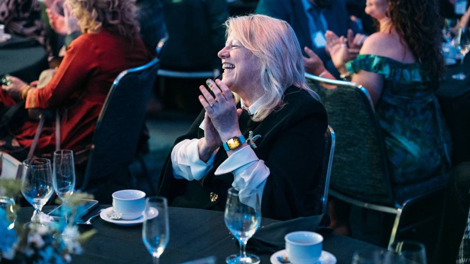 A woman claps an award winner